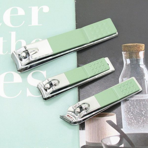 Three green nail clippers on a magazine page with blurred background